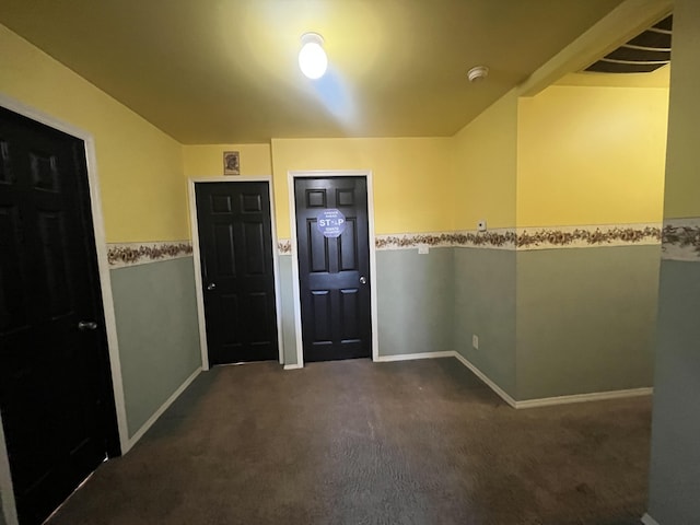 foyer entrance featuring baseboards and dark colored carpet