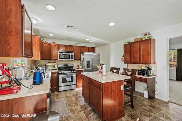 kitchen featuring stainless steel appliances, a sink, visible vents, light countertops, and a center island