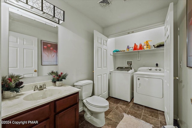 bathroom featuring toilet, visible vents, washer and clothes dryer, and vanity