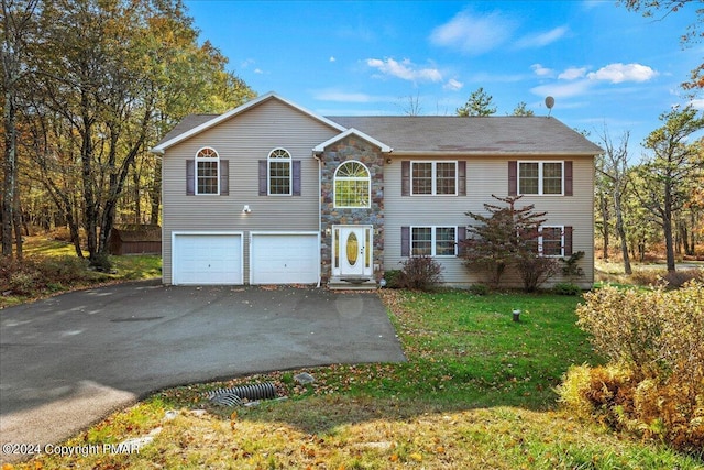 view of front of property with a front yard, stone siding, driveway, and an attached garage