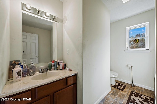 bathroom with toilet, baseboards, and vanity