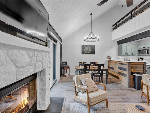 216 Snow Ridge Cir, Lake Harmony, PA 18624 - living area featuring ceiling fan, a fireplace, light wood-style floors, a chandelier, and high vaulted ceiling