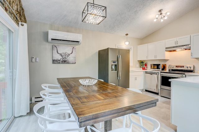 kitchen with light floors, baseboard heating, appliances with stainless steel finishes, an AC wall unit, and under cabinet range hood