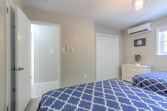 bedroom featuring a closet, a wall mounted air conditioner, and wood finished floors