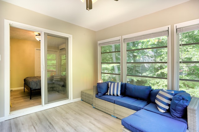 living area featuring ceiling fan, a wall mounted AC, wood finished floors, and baseboards