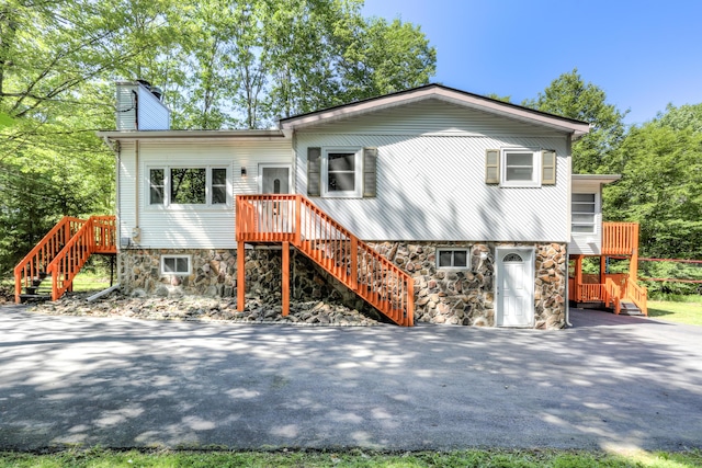 view of front of house with aphalt driveway, a chimney, and stairs