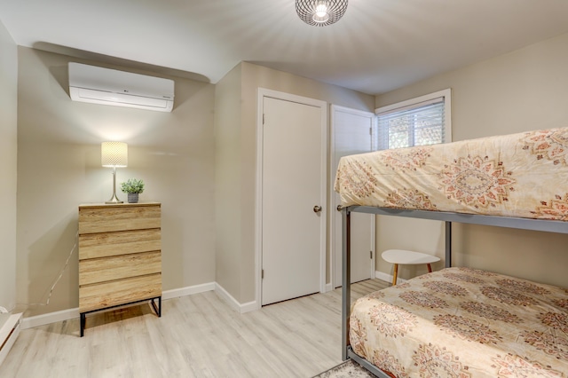 bedroom with a baseboard heating unit, baseboards, wood finished floors, and a wall mounted AC