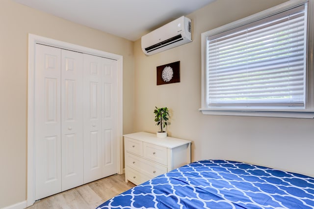 bedroom with a closet, a wall mounted air conditioner, and light wood finished floors