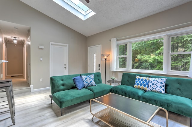 living room featuring vaulted ceiling, a textured ceiling, baseboards, and light wood-style floors