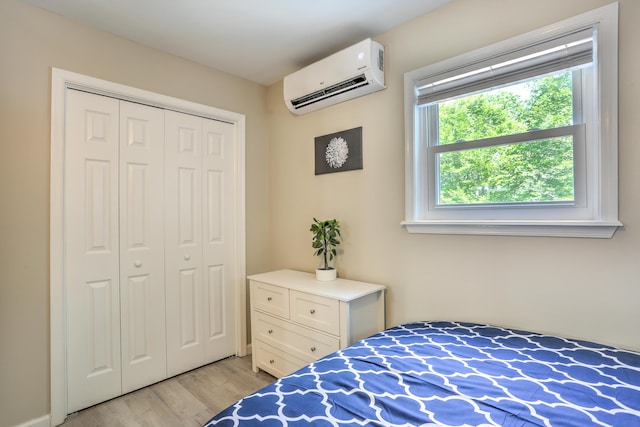 bedroom featuring light wood-style flooring, a closet, and a wall mounted air conditioner