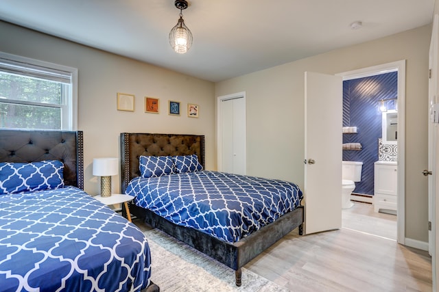 bedroom featuring a closet, baseboard heating, wood finished floors, and connected bathroom