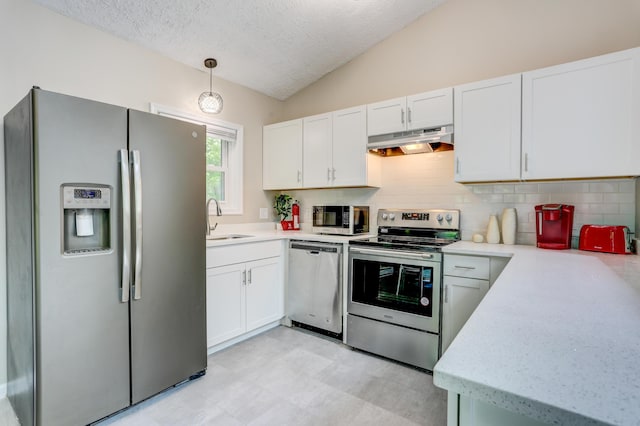 kitchen featuring under cabinet range hood, stainless steel appliances, a sink, white cabinetry, and vaulted ceiling