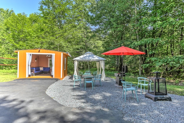 view of patio with a gazebo, a shed, an outdoor structure, and outdoor dining space