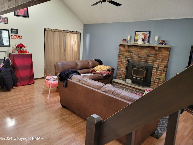 living room with a wood stove, lofted ceiling, ceiling fan, and wood finished floors