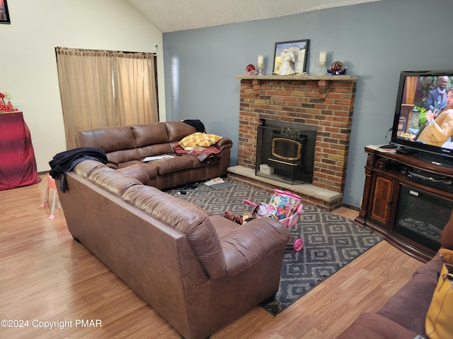 living room featuring wood finished floors, a wood stove, and vaulted ceiling