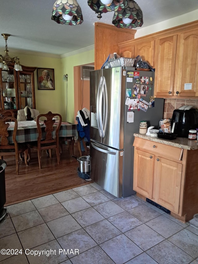 kitchen with light tile patterned floors, stainless steel fridge with ice dispenser, light countertops, crown molding, and tasteful backsplash