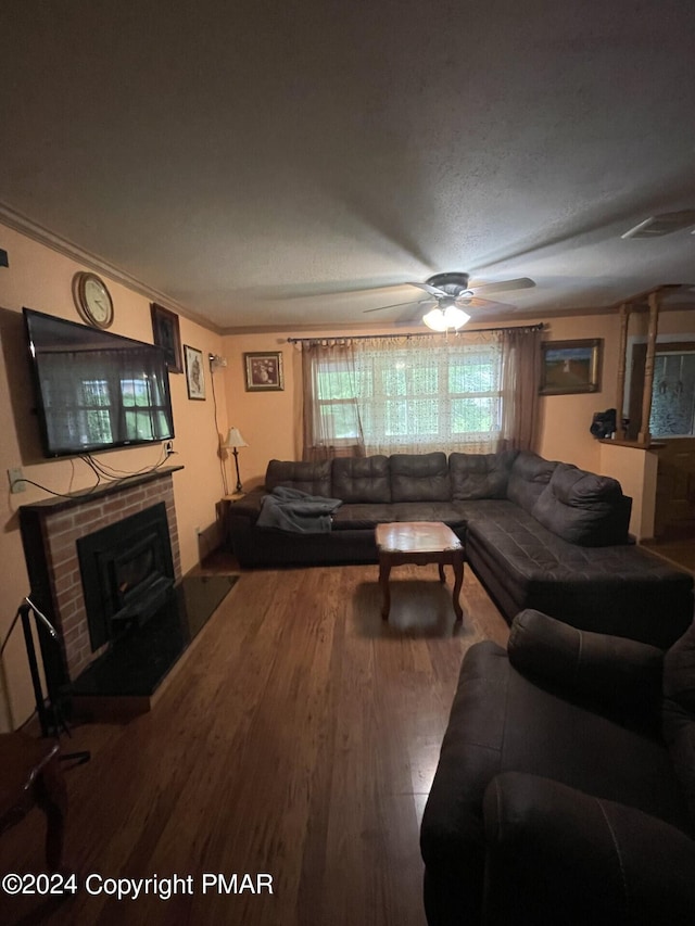 living room with ceiling fan, a brick fireplace, wood finished floors, and ornamental molding