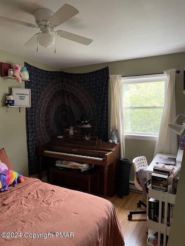 bedroom with light wood-style flooring, a baseboard heating unit, and ceiling fan