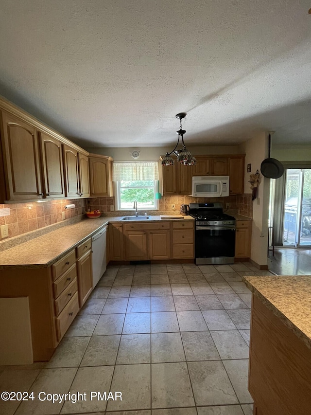 kitchen featuring white appliances, light tile patterned flooring, a sink, light countertops, and backsplash