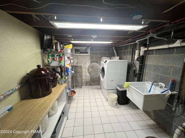 unfinished basement featuring washing machine and clothes dryer, tile patterned flooring, and a sink