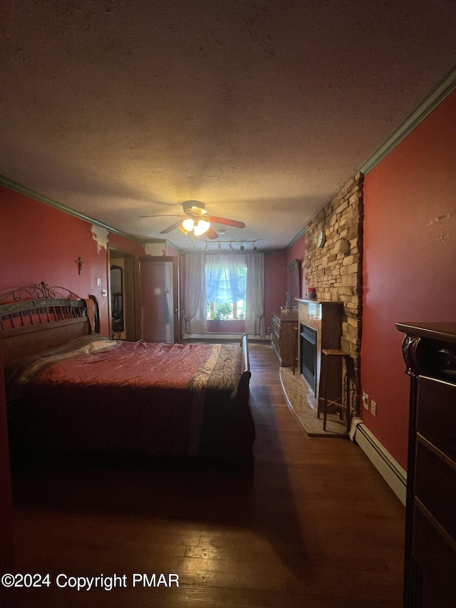 bedroom featuring crown molding, a fireplace, wood finished floors, a textured ceiling, and a baseboard radiator