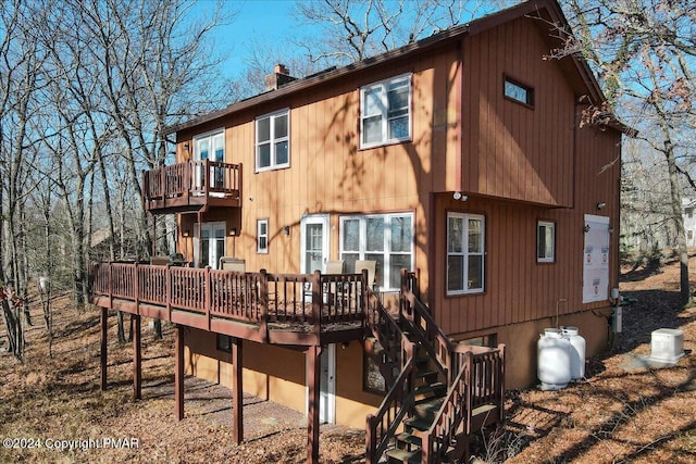 back of property with a deck, stairway, and a chimney