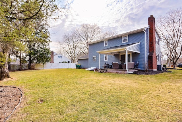 back of property with a lawn, central AC unit, a chimney, and fence