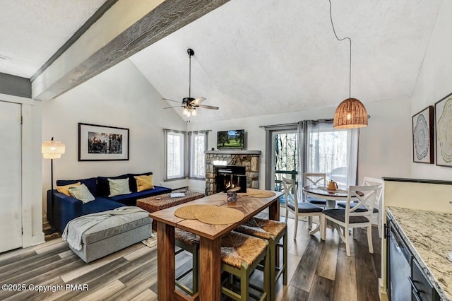 living room with ceiling fan, dark wood-type flooring, a textured ceiling, and a fireplace