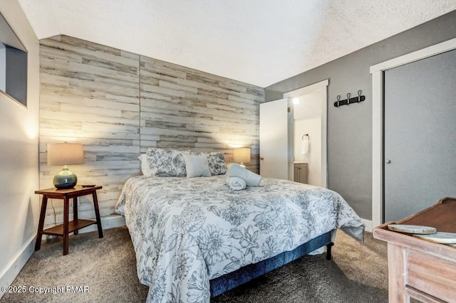 bedroom featuring carpet flooring, connected bathroom, a textured ceiling, and wooden walls