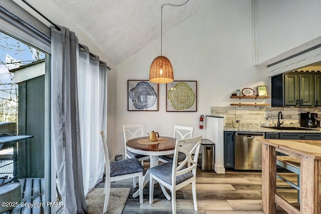 dining area featuring vaulted ceiling, sink, and light wood-type flooring