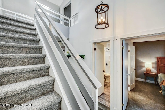 stairway featuring a towering ceiling and carpet floors