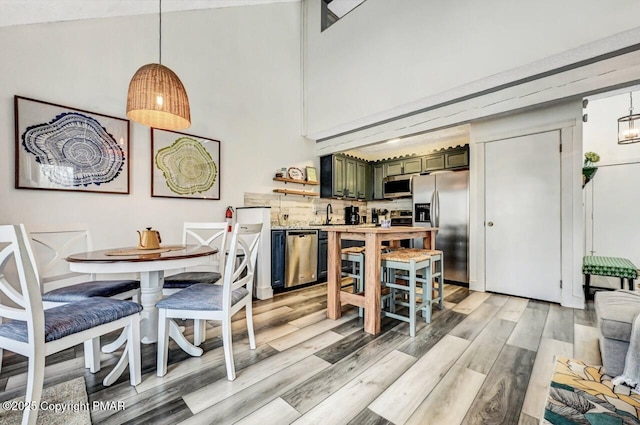 dining room featuring a towering ceiling and light wood-type flooring