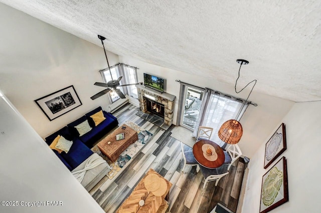 living room with hardwood / wood-style flooring, vaulted ceiling, a textured ceiling, and ceiling fan