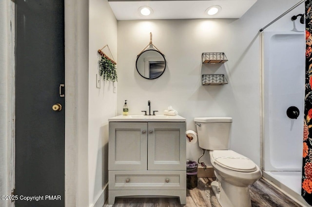 bathroom featuring hardwood / wood-style flooring, vanity, toilet, and walk in shower