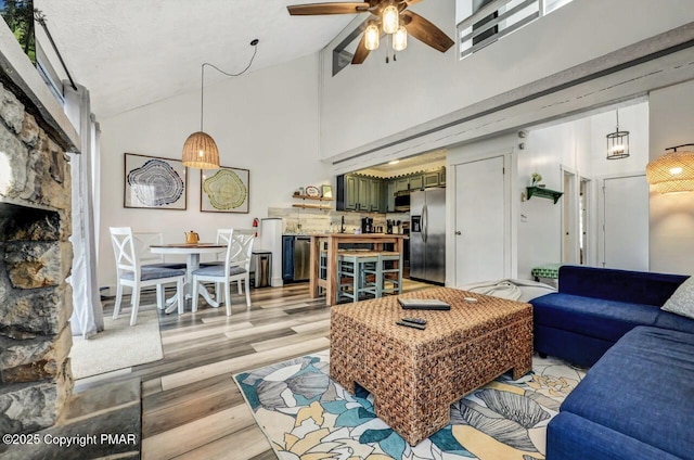 living room with ceiling fan, light hardwood / wood-style floors, and high vaulted ceiling