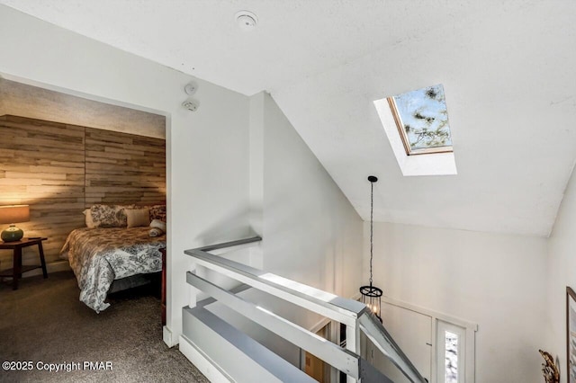 staircase with carpet flooring, wooden walls, and lofted ceiling with skylight