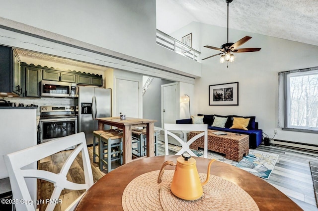 dining space with a baseboard heating unit, hardwood / wood-style flooring, high vaulted ceiling, and ceiling fan