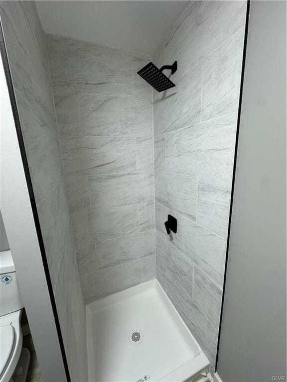 full bath with a tile shower and toilet