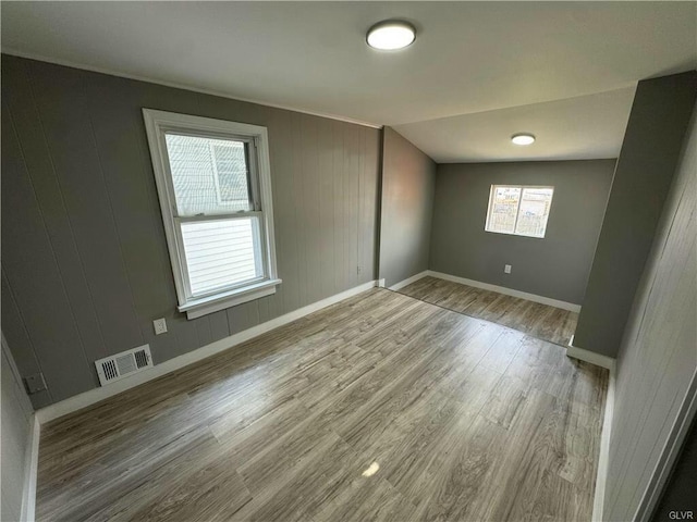 empty room with baseboards, visible vents, and wood finished floors