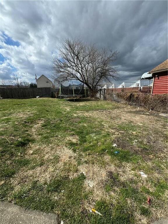 view of yard featuring a trampoline and fence