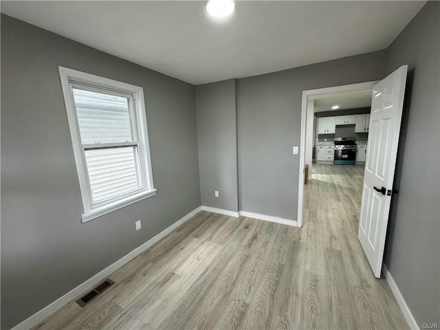 unfurnished room with light wood-style flooring, baseboards, and visible vents