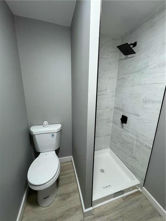 bathroom with wood finished floors, baseboards, and a shower stall