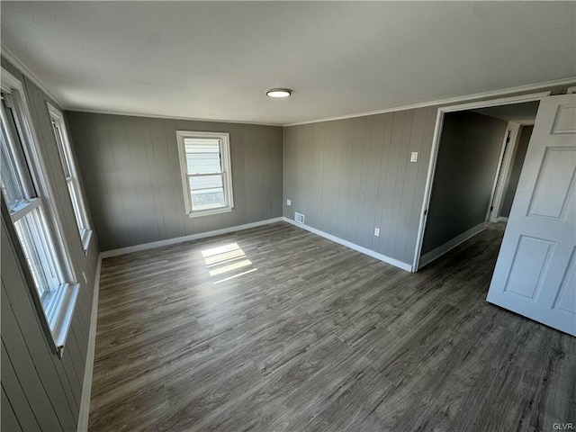 spare room with dark wood-style flooring, ornamental molding, and baseboards