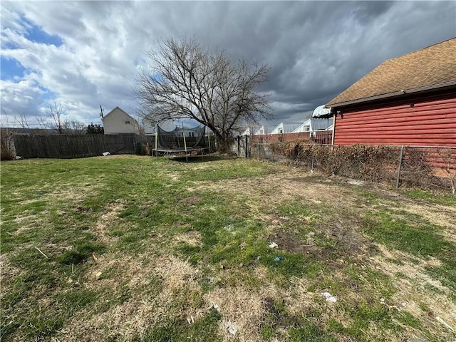 view of yard featuring a trampoline and a fenced backyard