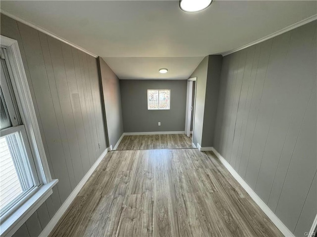 spare room featuring ornamental molding, baseboards, and wood finished floors