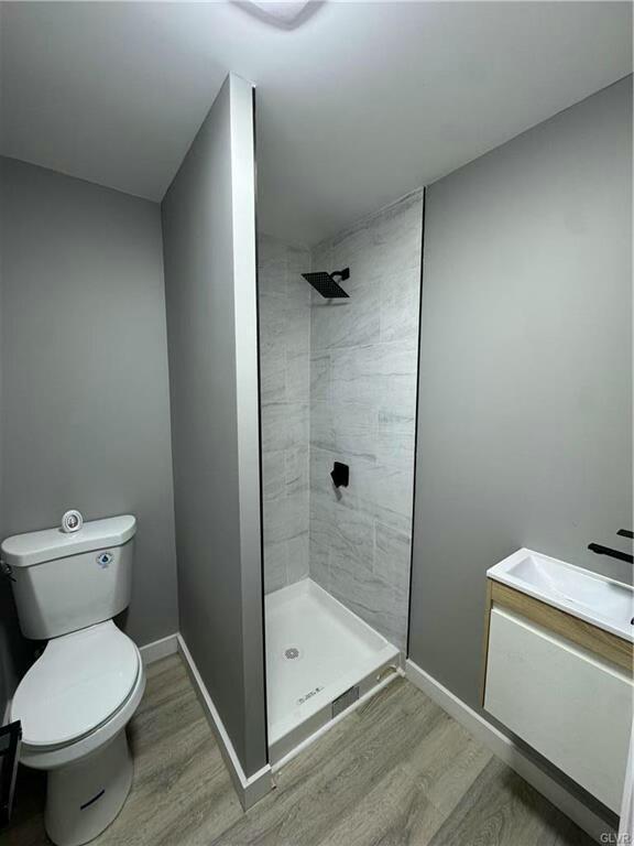 full bath with toilet, a shower stall, and wood finished floors