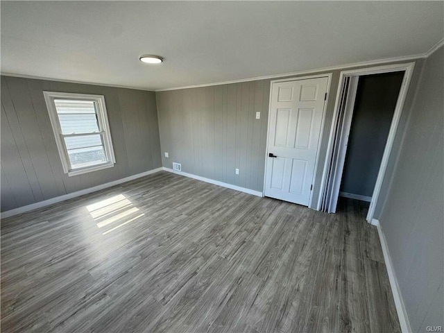 unfurnished bedroom featuring dark wood finished floors, baseboards, visible vents, and ornamental molding