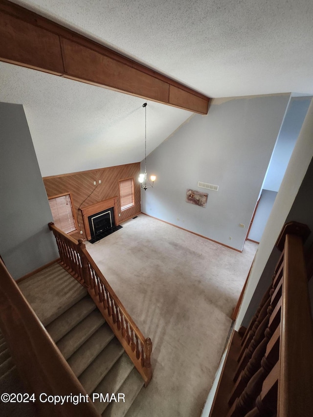 stairs featuring a textured ceiling, vaulted ceiling with beams, and carpet flooring