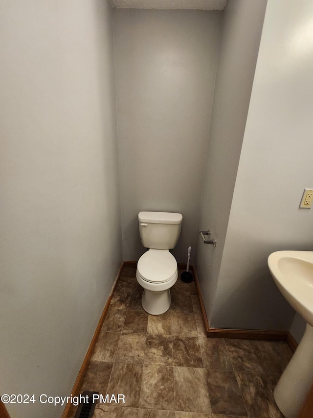 bathroom with toilet and baseboards