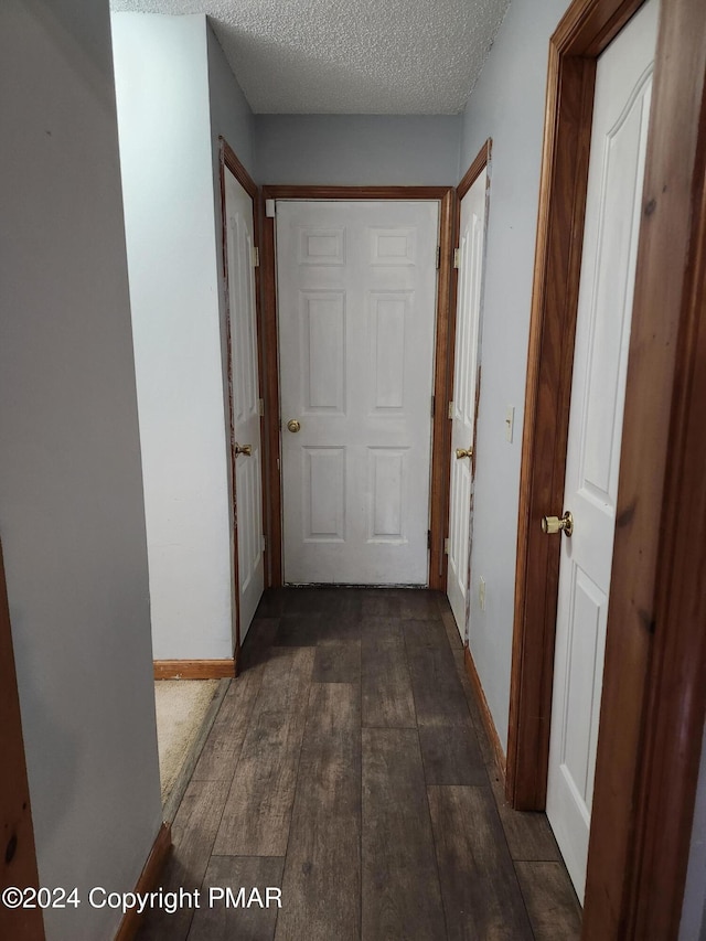 hall with baseboards, a textured ceiling, and dark wood finished floors